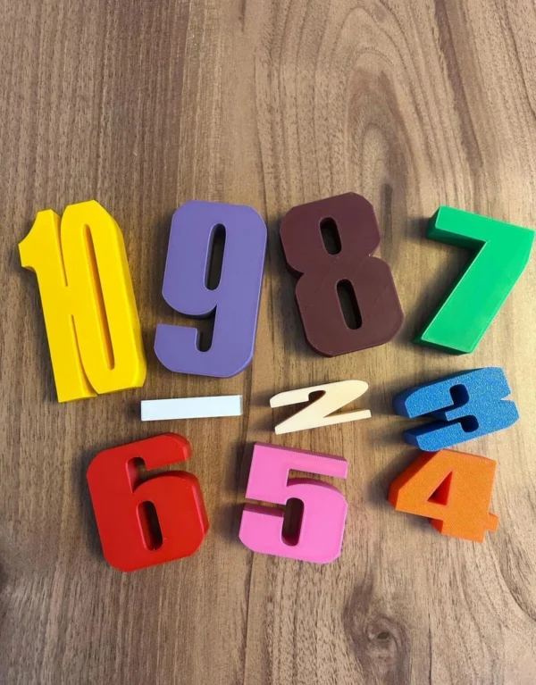 Ahşap zemin üzerinde dağınık halde duran renkli 3D baskı Montessori sayı blokları ve işlem sembolleri, okul öncesi eğitici oyuncak seti.