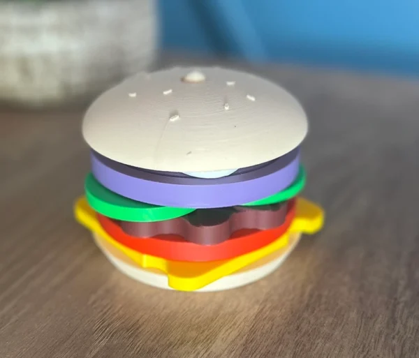 3D baskı Montessori hamburger oyuncak tamamen sıralanmış şekilde masa üzerinde duruyor, katmanlı parçalar çocuklar için eğitici oyuncağı tamamlıyor.