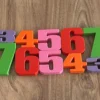 Ahşap zemin üzerinde 1’den 10’a kadar çiftli olarak dizilmiş Montessori renkli 3D baskı sayı blokları seti.