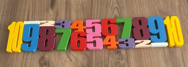 Ahşap zemin üzerinde 1’den 10’a kadar çiftli olarak dizilmiş Montessori renkli 3D baskı sayı blokları seti.