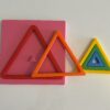 Montessori üçgen şekil bulmaca – renkli üçgen parçaların 3D baskılı pembe bir tabla üzerinde yerleştirilmiş hali.