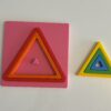 Montessori üçgen puzzle parçalarının tablaya yerleştirilmeye başladığı süreç, bazı parçalar dışarıda.