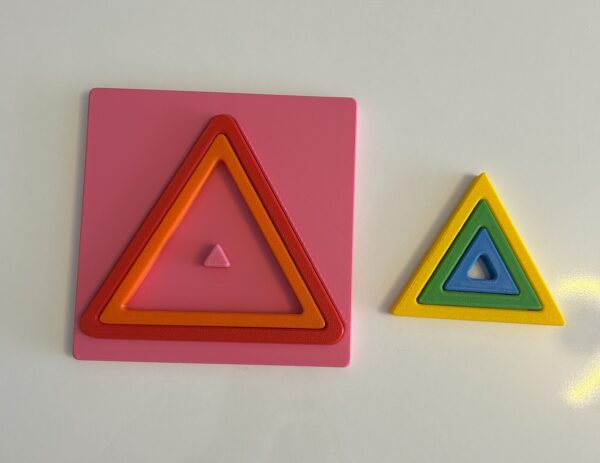 Montessori üçgen puzzle parçalarının tablaya yerleştirilmeye başladığı süreç, bazı parçalar dışarıda.